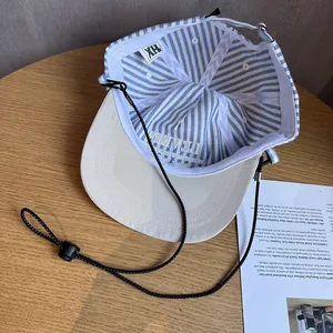 Blue striped baseball cap with beige brim and adjustable windproof cord on wood table