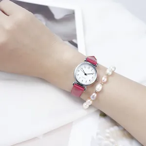 Close-up of women's quartz watch with rose red leather strap and pearl bracelet