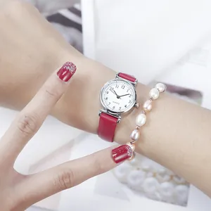 Close-up of a women's quartz watch with a red leather strap and pearl bracelet