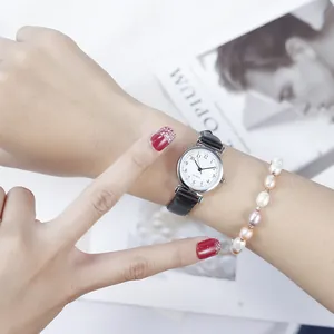 Detailed close-up of ladies minimalist quartz watch with thin leather strap and pearl bracelet