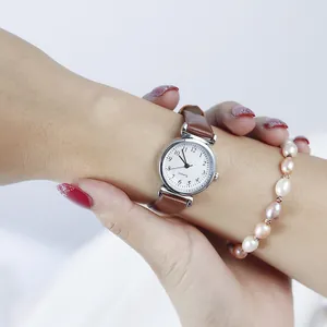 Close-up of elegant ladies' quartz watch with brown leather strap and silver dial on wrist
