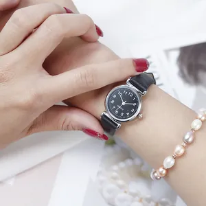 Detail of elegant ladies' black leather strap watch with small dial and pearl bracelet