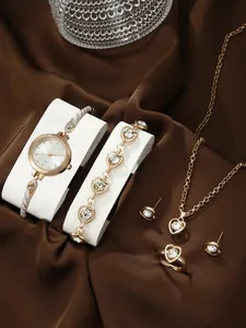 Detailed macro shot of rose gold heart jewelry set and elegant quartz watch on satin