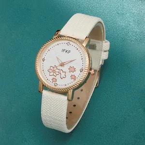 Detail van een wit leren horloge met een roségouden lunette en bloemenpatroon op de wijzerplaat