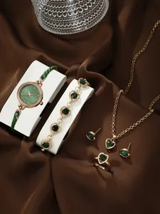 Detail of luxury green quartz watch set with matching emerald jewelry on satin