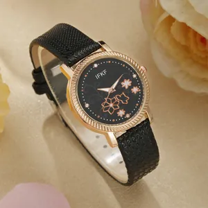 Detail van roségouden horloge met zwarte bloemenwijzerplaat en zwart leren bandje