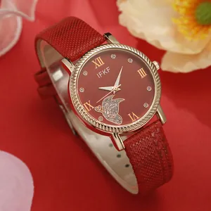 Macro view of women's red quartz watch featuring a gold butterfly design and leather strap
