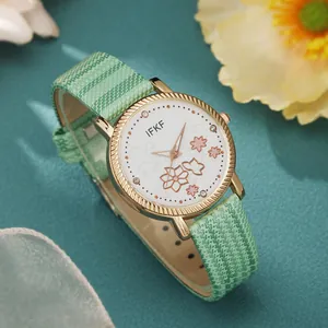 Detail van elegant dameshorloge met bloemenwijzerplaat en mintgroene leren band met goud