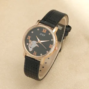 Close-up of rose gold watch with black leather strap and rhinestone butterfly on dial