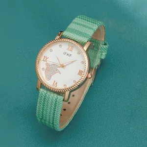 Close-up of rose gold watch dial with diamond butterfly pattern and green strap