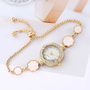 Montre bracelet fleur dorée élégante avec lunette en strass et cadran en nacre