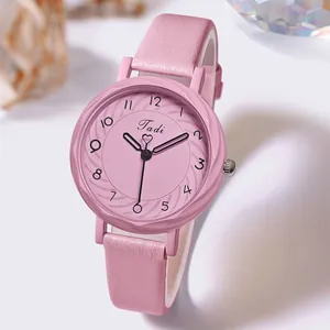 Détail d'une montre rose pour femme avec cadran à texture radiale et bracelet fin