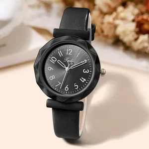 Detail of black quartz watch featuring faceted glass and leather strap on a beige table