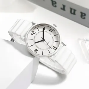Detailaufnahme einer weißen Quarzuhr mit Silikonarmband auf einem minimalistischen Sockel