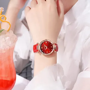 Détail d'une montre à cadran dégradé rouge, lunette en verre facetté et bracelet en cuir au poignet