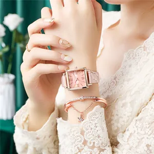 Détail d'une montre carrée or rose avec cadran rose et bracelet assorti à breloque étoile