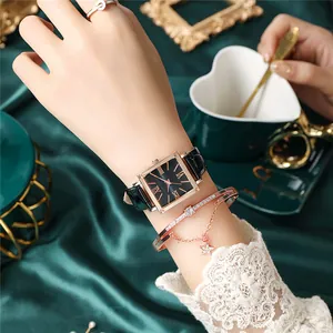 Gros plan d'une montre carrée noire et d'un bracelet en or rose sur de la soie