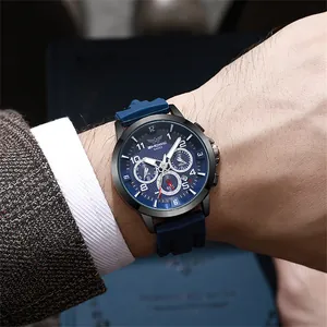 Gros plan d'un chronographe avec cadran bleu et bracelet en silicone sous une manche de costume