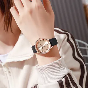 Close-up of rose gold quartz watch with champagne sunray dial and black silicone strap