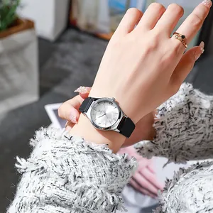 Close-up of women's quartz watch with silver floral dial and black silicone strap on wrist