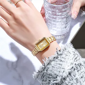 Detail of elegant gold square quartz watch with metal strap on model holding a glass