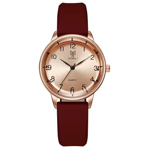 Macro detail of quartz watch with rose gold metal case and dark reddish-brown silicone strap
