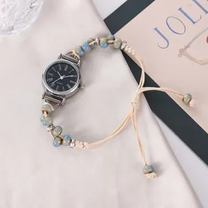 Détail de montre à quartz avec cadran noir et bracelet perlé sur tissu de soie
