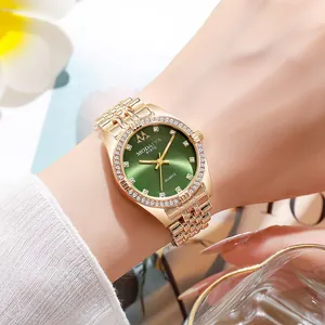 Close-up of luxury gold women's watch with green dial and rhinestones on wrist