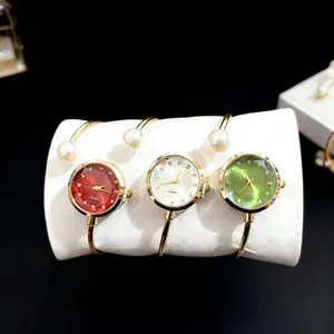 Détail de montres bracelets dorées avec cadrans colorés et ornements en perles fines
