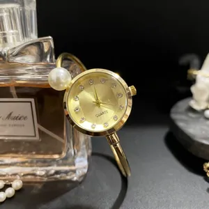 Montre bracelet quartz dorée élégante pour femme avec cadran rond et perle