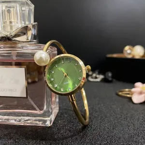 Détails d'une montre bracelet dorée élégante avec cadran vert et perle nacrée