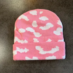 Detaillierte Nahaufnahme der rosa Strickmütze mit weißen Wolkenmustern und Textur