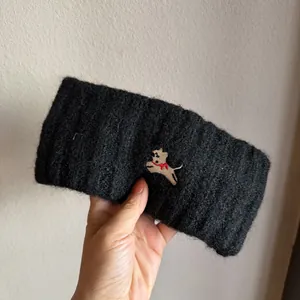 Macro view of plush knit fabric and embroidered puppy detail on the black winter headband