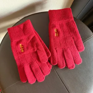 Detailed close-up of red knit gloves featuring golden Chinese character embroidery