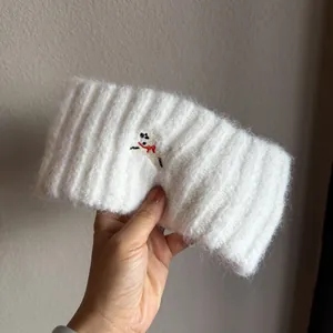 Close-up of white knit headband featuring fuzzy texture and cute puppy embroidery