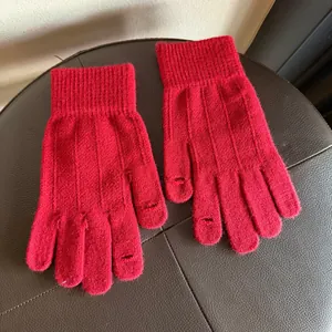 Detail of red knit gloves showing functional fingertip openings for touchscreen use