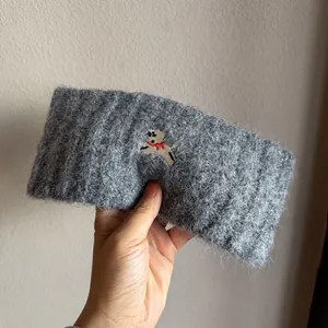 Close-up of grey knit headband featuring embroidered puppy with a red bow detail