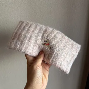Detail view of pink knit headband with delicate embroidered puppy and wool texture