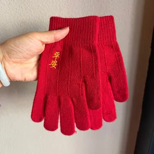 Close-up of red knitted gloves with yellow embroidery and ribbed wrist cuffs