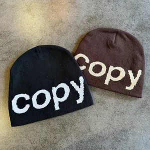 Close-up of black and brown knit beanies featuring white embroidered copy lettering