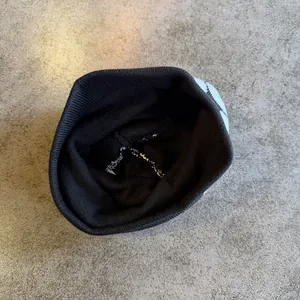 Dettaglio interno di un berretto in maglia nera che mostra cuciture e materiale morbido
