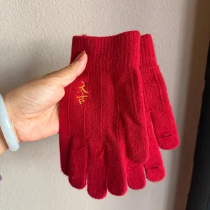 Detail of red knit gloves with lucky gold embroidery and touchscreen finger slits