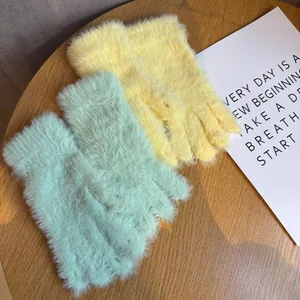 Détail de gants d'hiver en peluche macaron vert menthe et jaune sur une table en bois