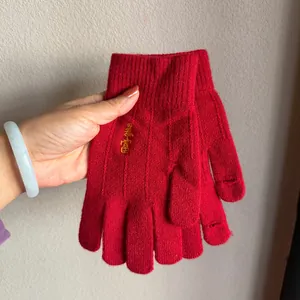 Macro detail of red knit gloves with gold embroidery and functional touchscreen openings