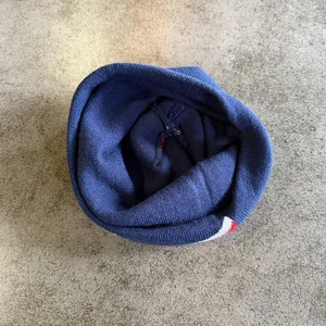 Detail van de marineblauwe gebreide muts met dikke textuur en interne stiksels