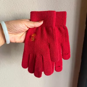 Close-up of red knit gloves featuring gold Good Luck embroidery and ribbed cuffs