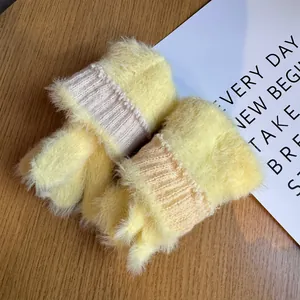 Gros plan de gants en peluche tricotés jaunes avec poignets côtelés et texture douce