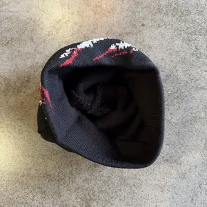 Detail of black knit beanie featuring red and white jacquard mountain pattern design