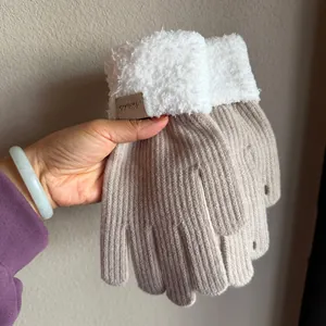 Detail of khaki knit gloves with white faux fur cuffs and a leather brand patch