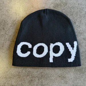 Detail view of the fine knit texture and woven copy lettering on this black beanie hat